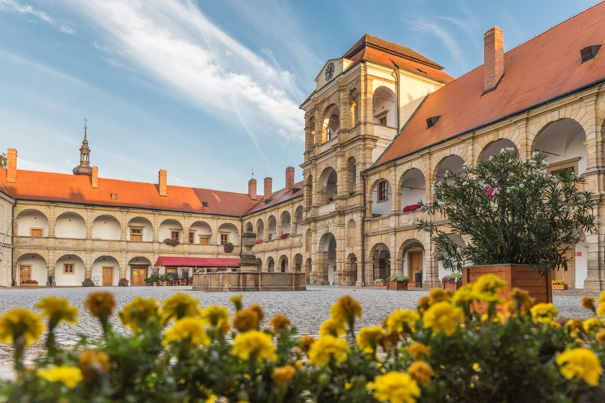 ein Gebäude mit einem Uhrenturm und einem Innenhof mit gelben Blumen